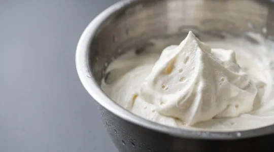 Bol de crème fouettée montrant sa texture aérienne et sa structure moléculaire de matière grasse laitière