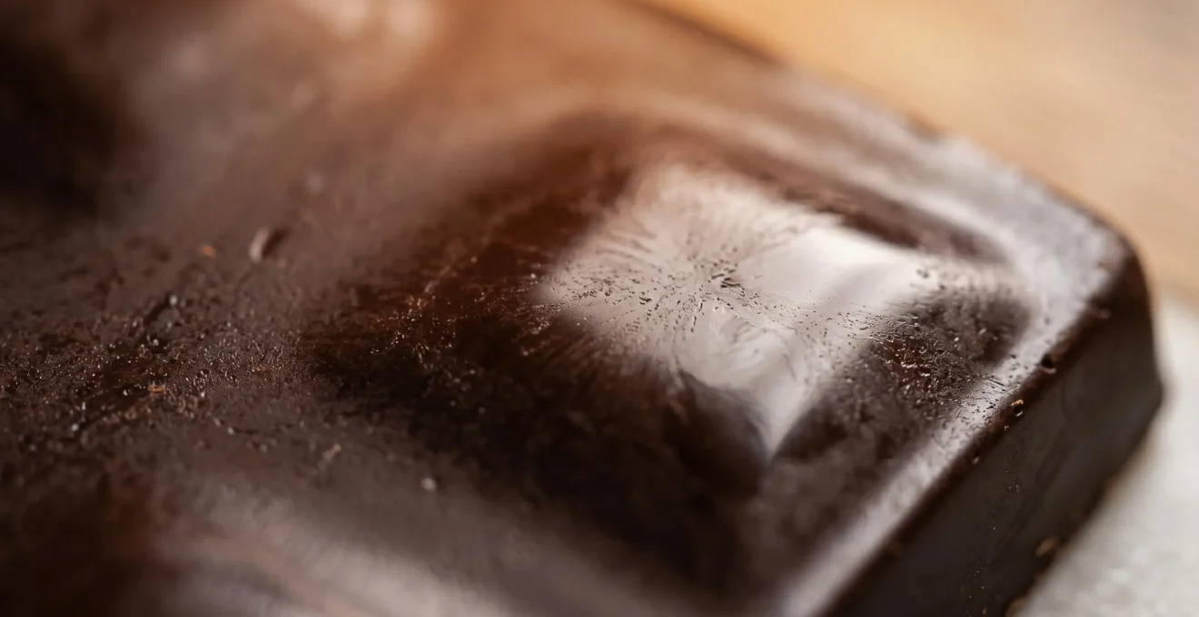 Gros plan macro sur des cristaux de beurre de cacao en formation dans du chocolat tempéré, texture brillante et lisse