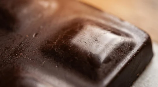 Gros plan macro sur des cristaux de beurre de cacao en formation dans du chocolat tempéré, texture brillante et lisse