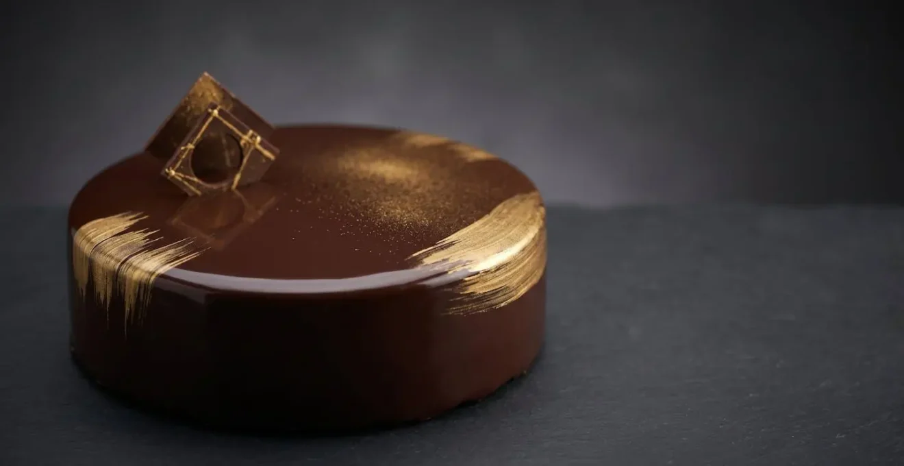 Entremet moderne décoré avec élégance de touches dorées subtiles sur glaçage miroir chocolat noir